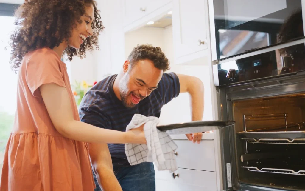 Disabled man cooking pizza with support worker