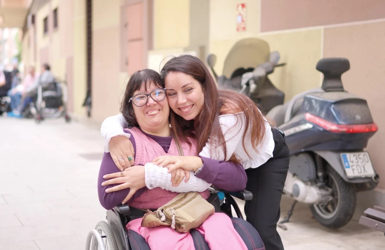 Disabled woman in wheelchair hugging friend