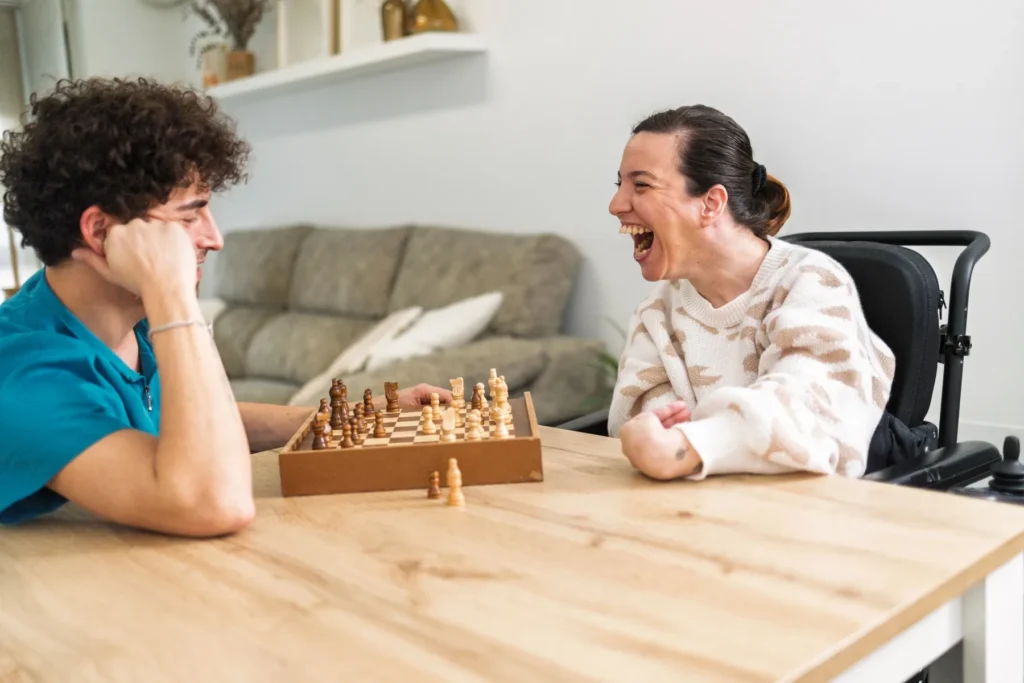 Disabled woman playing chess with support worker